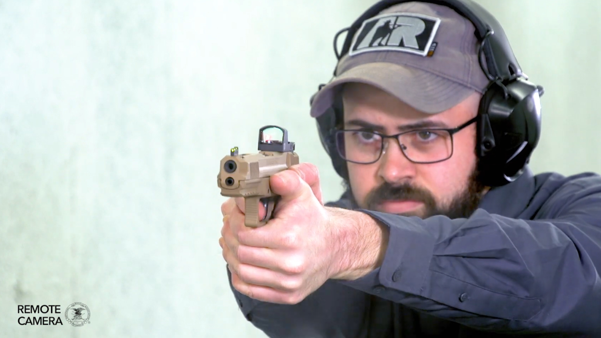 Man wearing protective gear shooting brown Ruger pistol indoors