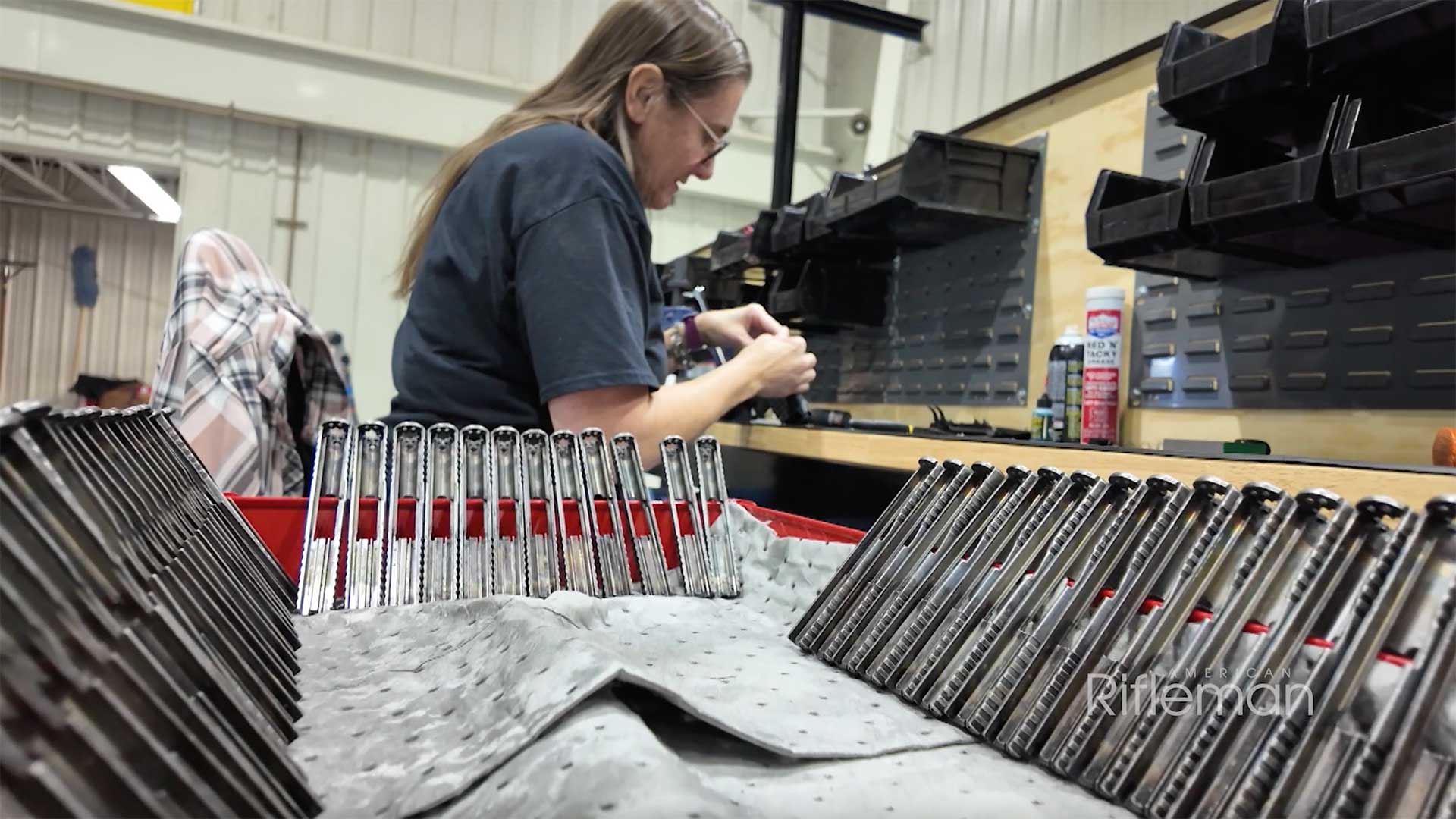 Woman assembling KelTec PR57 handgun slides at a workbench.