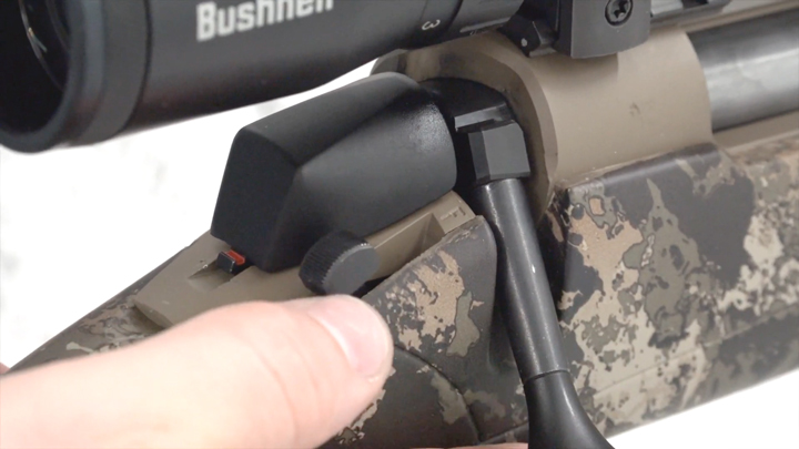 Up-close view of rifle&#x27;s safety with a shooter&#x27;s thumb behind.