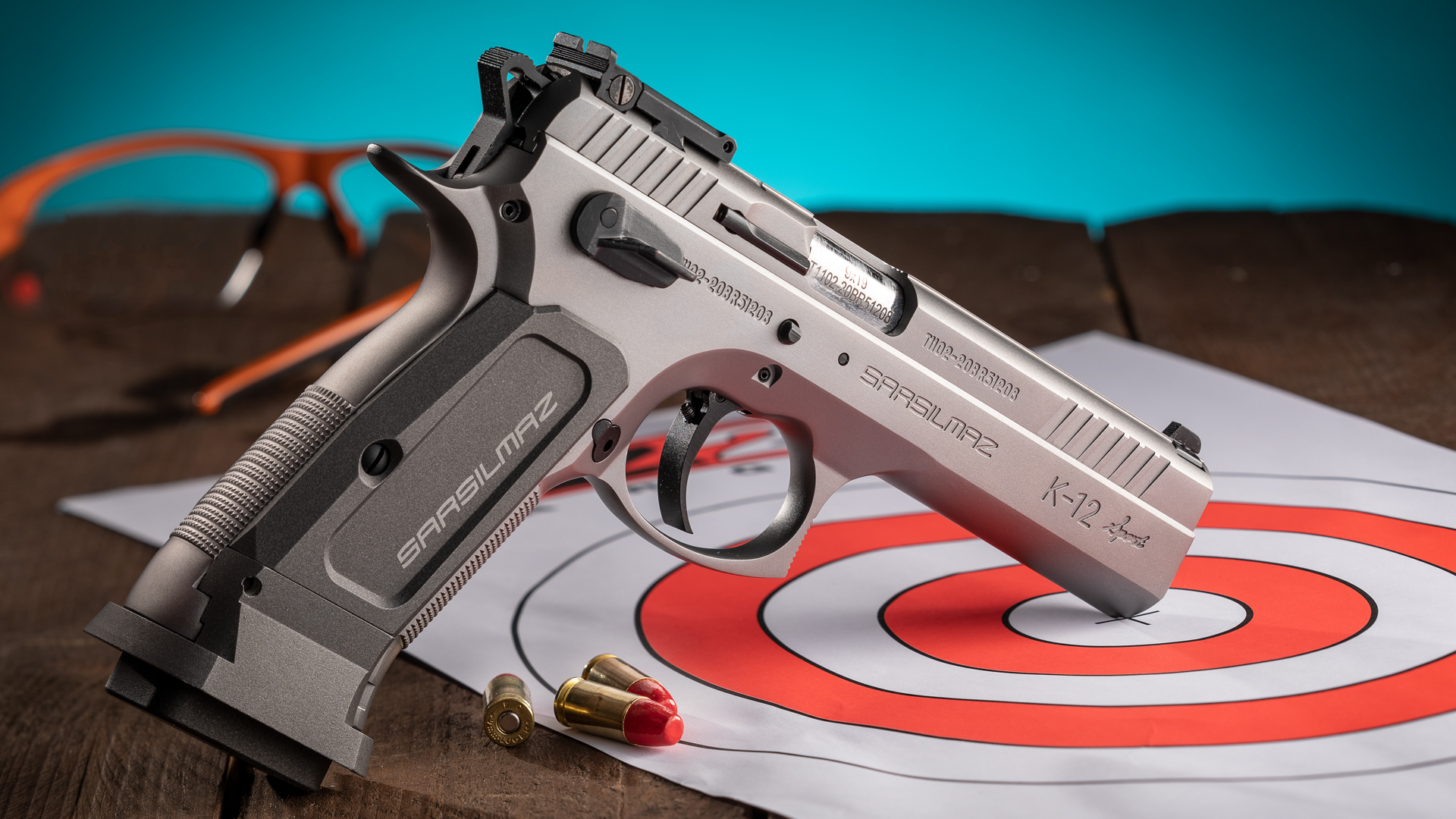 SAR USA K12 Sport stainless steel pistol right-side dynamic view on table with ammunition and target orange white circles