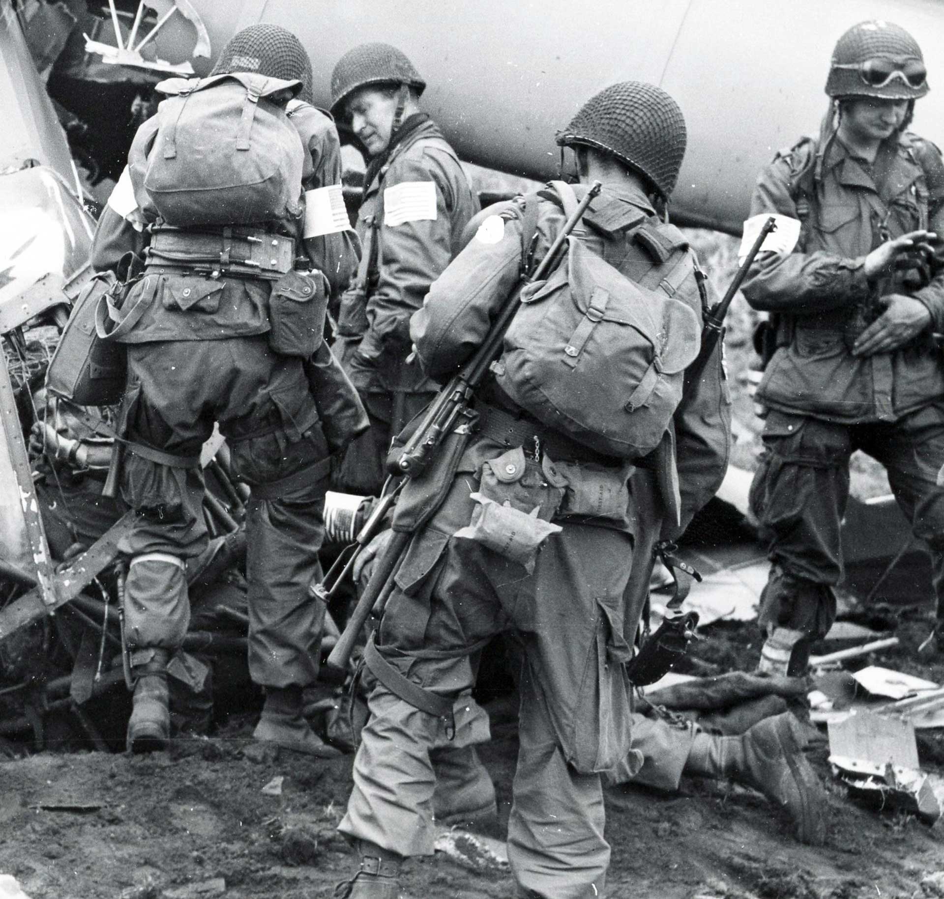 U.S. airborne troops prepare to board a C47 transport aircraft while armed with M1 carbines.