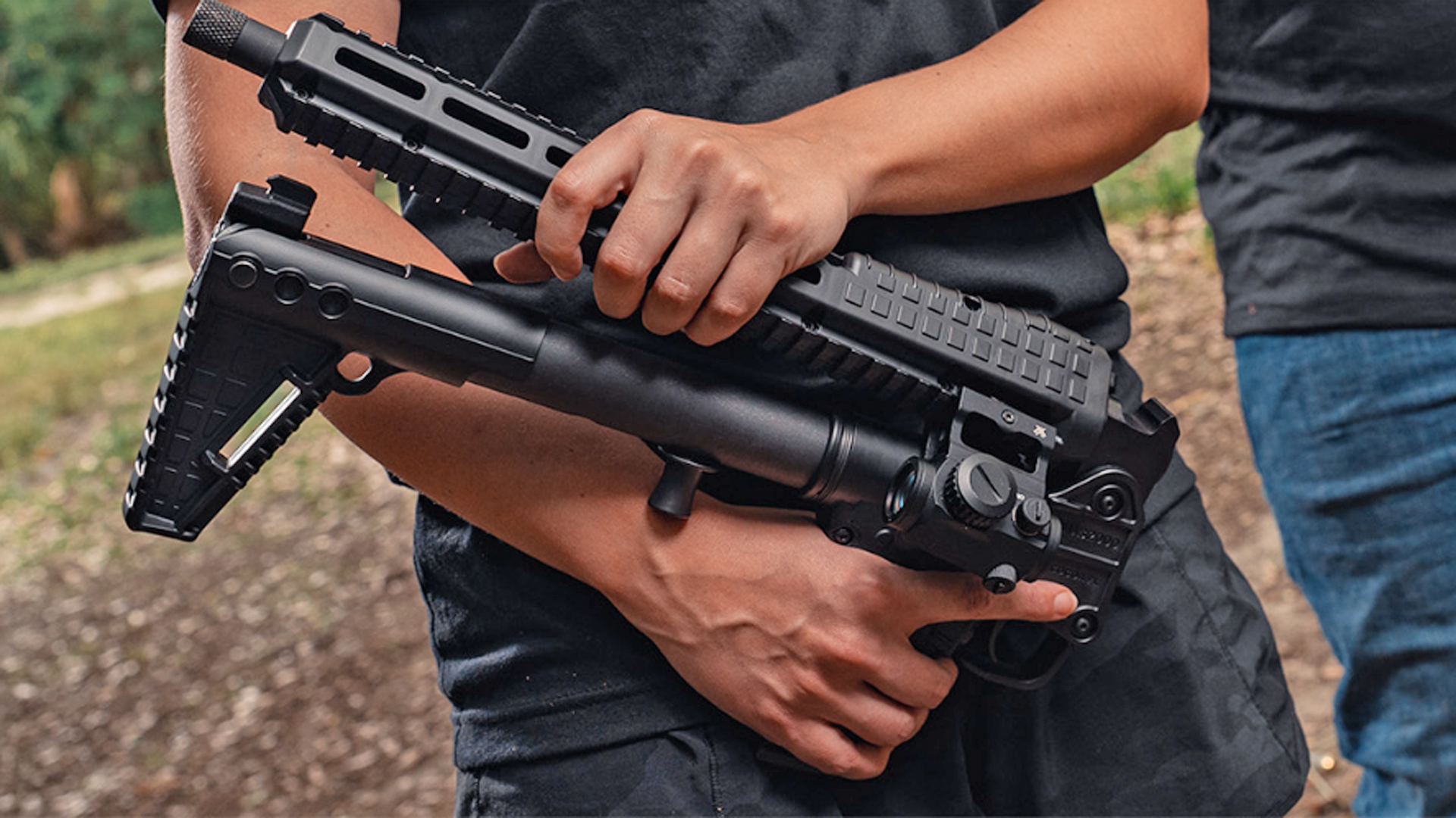 Man folding the KelTec SUB2000 10 mm Auto on an outdoor range.