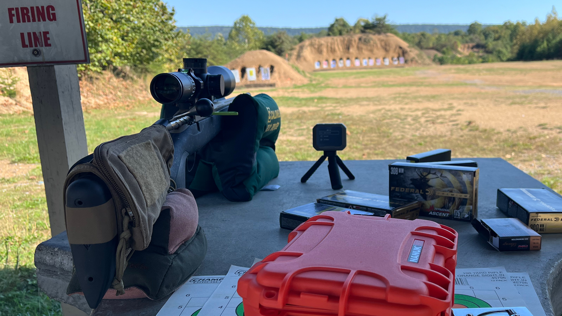 Tikka T3x RoughTech Superlite bolt-action hunting rifle on bench outdoors shooting range shown with gear on table targets in background