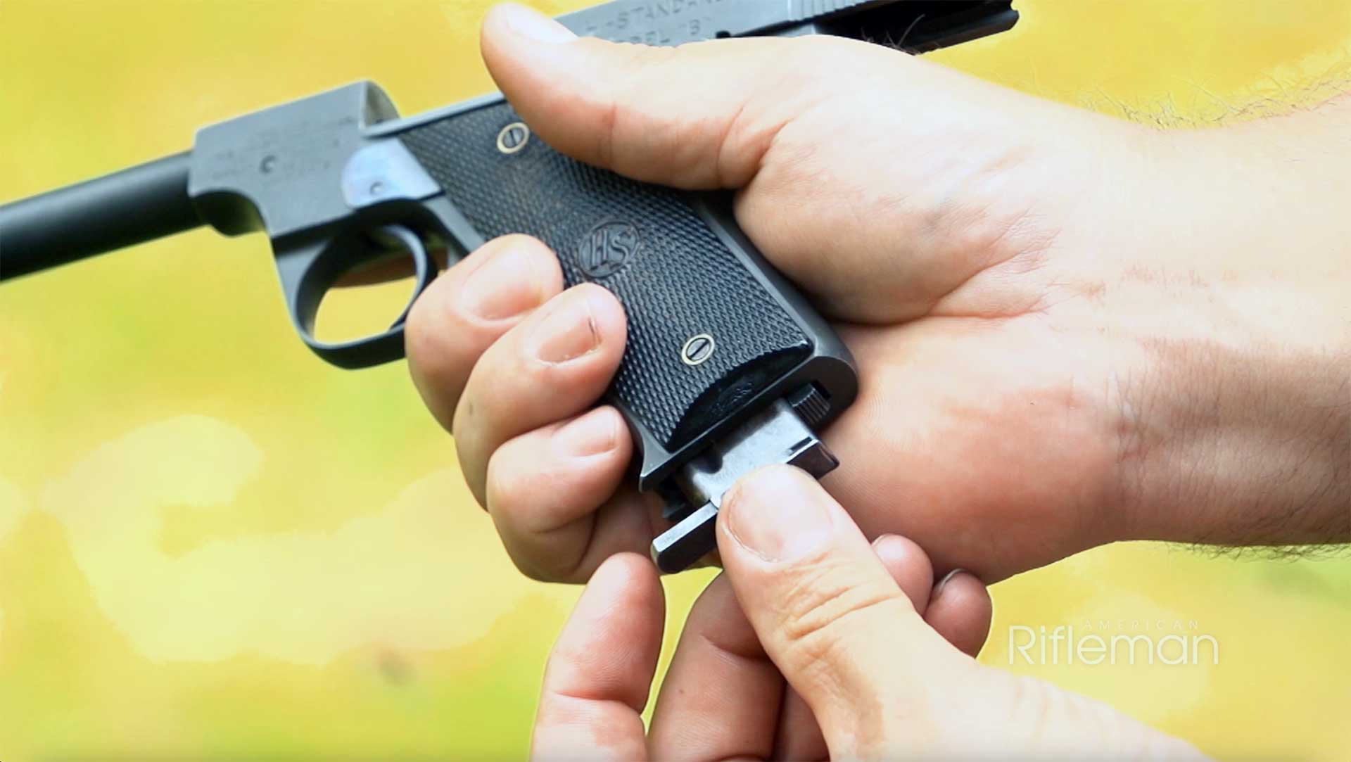 A man loading a magazine into a Hi-Standard Model B.