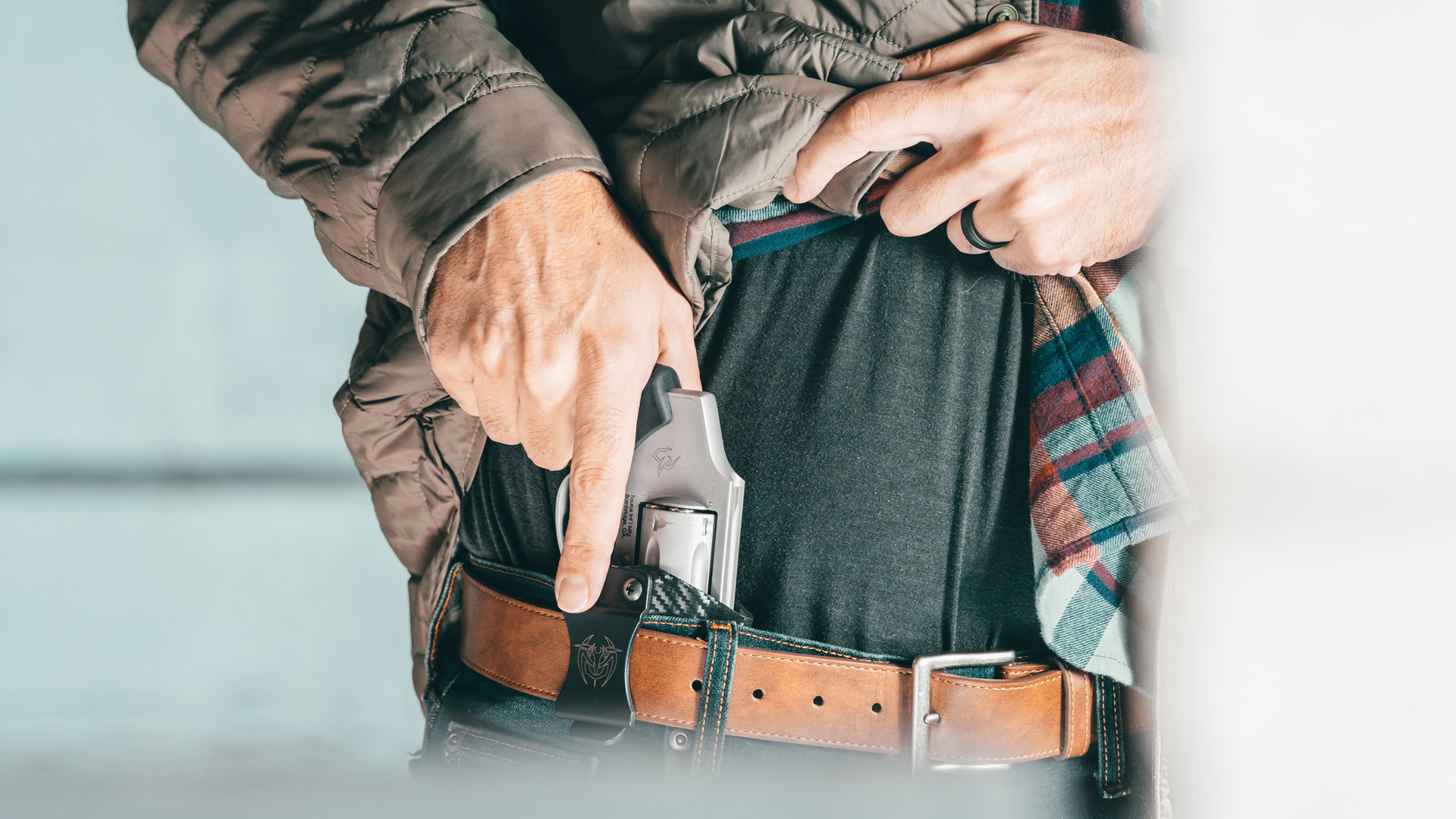 A man drawing the Taurus 650 revolver from an inside-the-waistband holster.