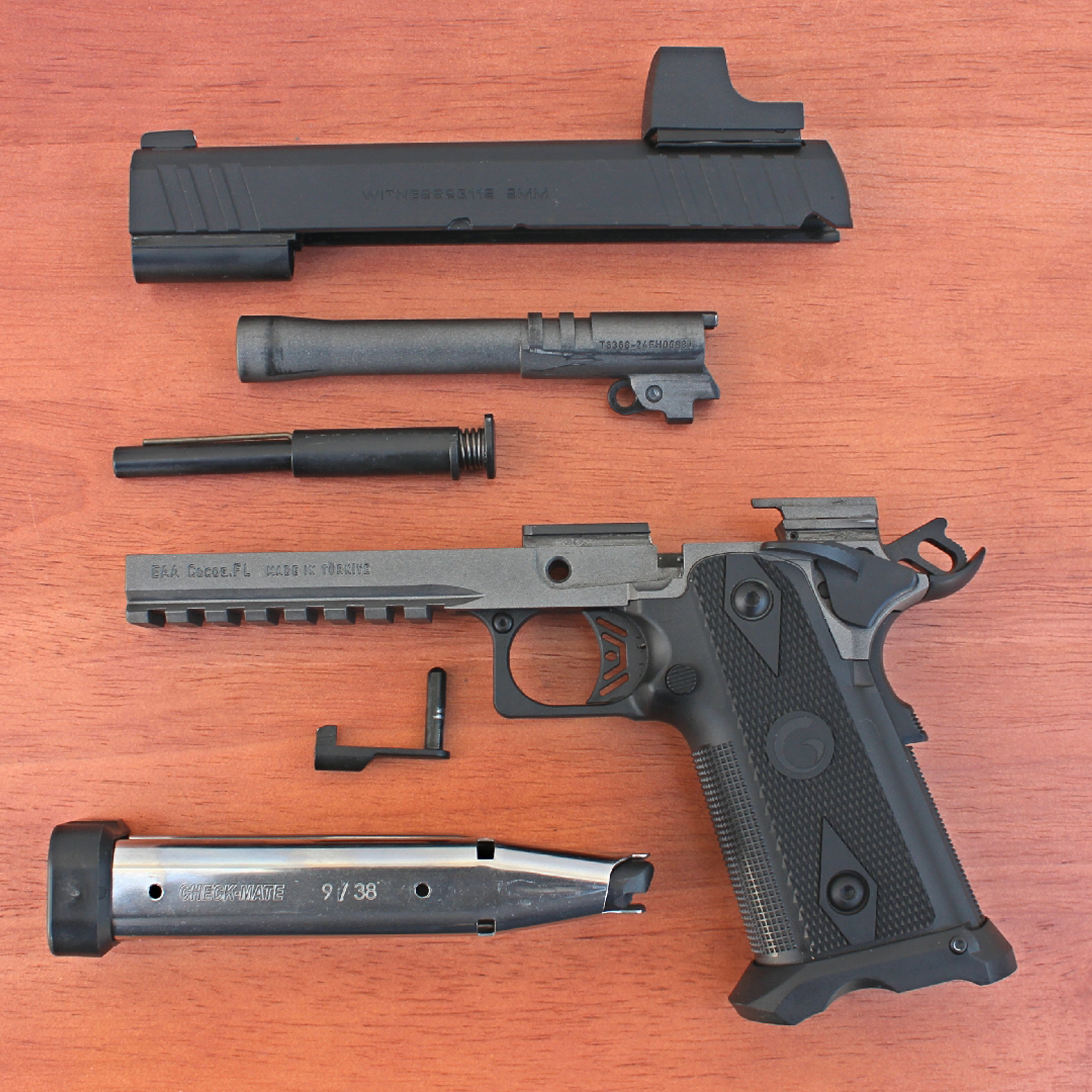 Exploded parts view of EAA Corp Girsan Witness 2311S Match pistol slide barrel spring frame grip magazine on wood table