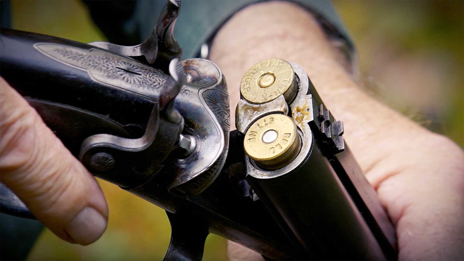 Two brass cartridges sitting inside the open action of a Howdah pistol.