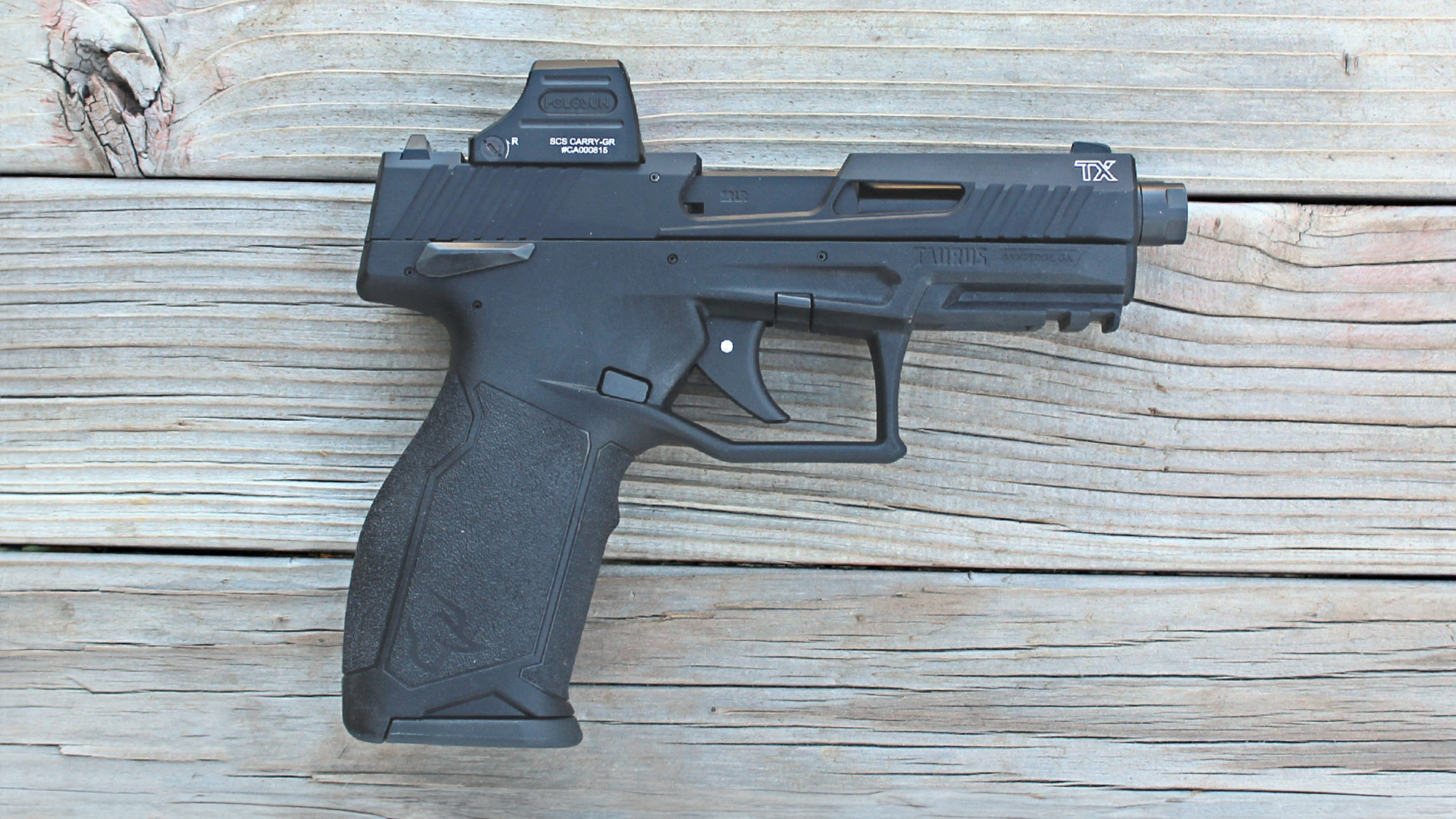 Taurus TX22 Black T.O.R.O. pistol 22LR gun right-side view with holosun optic shown on wood background