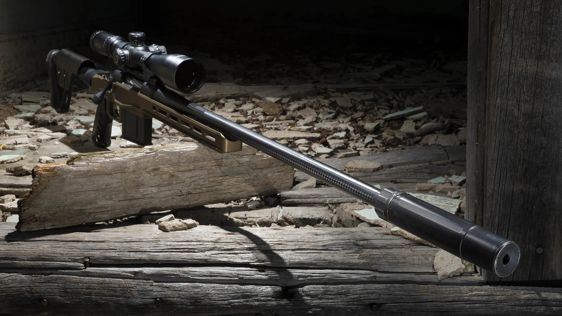 Bolt-action rifle shown with spotlight and suppressor silencer muzzle device attached