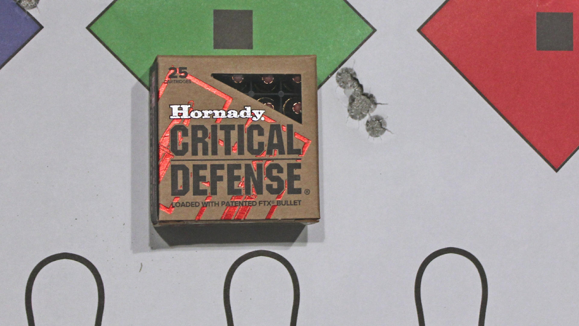 Box of Hornady Critical Defense 9 mm Luger ammunition shown next to target with bullet holes accuracy group size