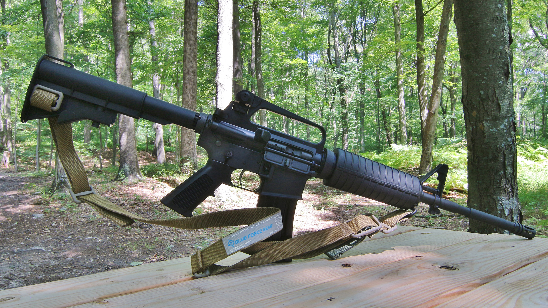 Bushmaster M4A2 Patrolman Carbine right-side view with sling on wood bench outdoor shooting range