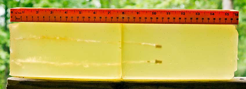 A block of yellow ordnance gelatin showing two .22 Magnum projectiles next to a red ruler.