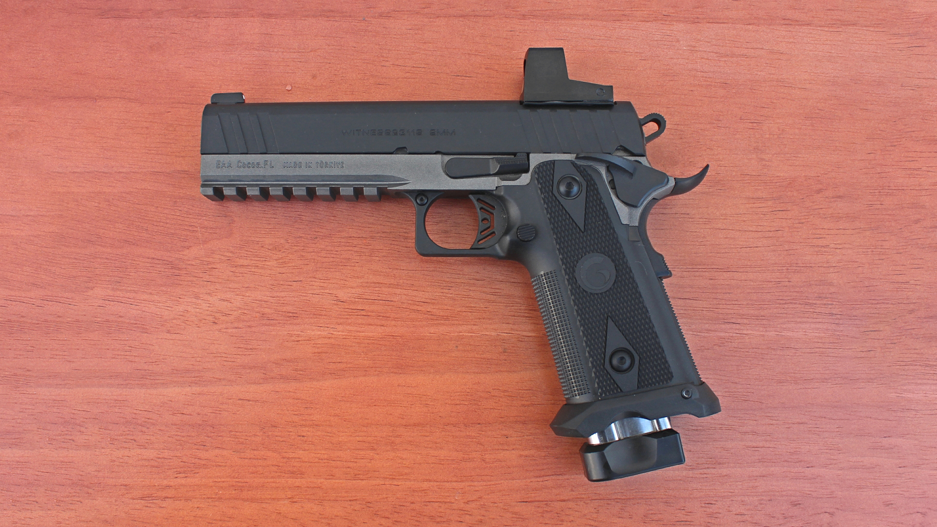 EAA Corp Girsan Witness2311S Match pistol left-side view on wood table shown with FAR-DOT red-dot optic attached to black slide over gray frame and black polymer grip.