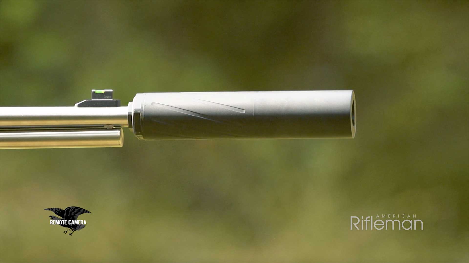 A silver rifle barrel equipped with a Black Silencer Central Banish 46 suppressor aims downrange.