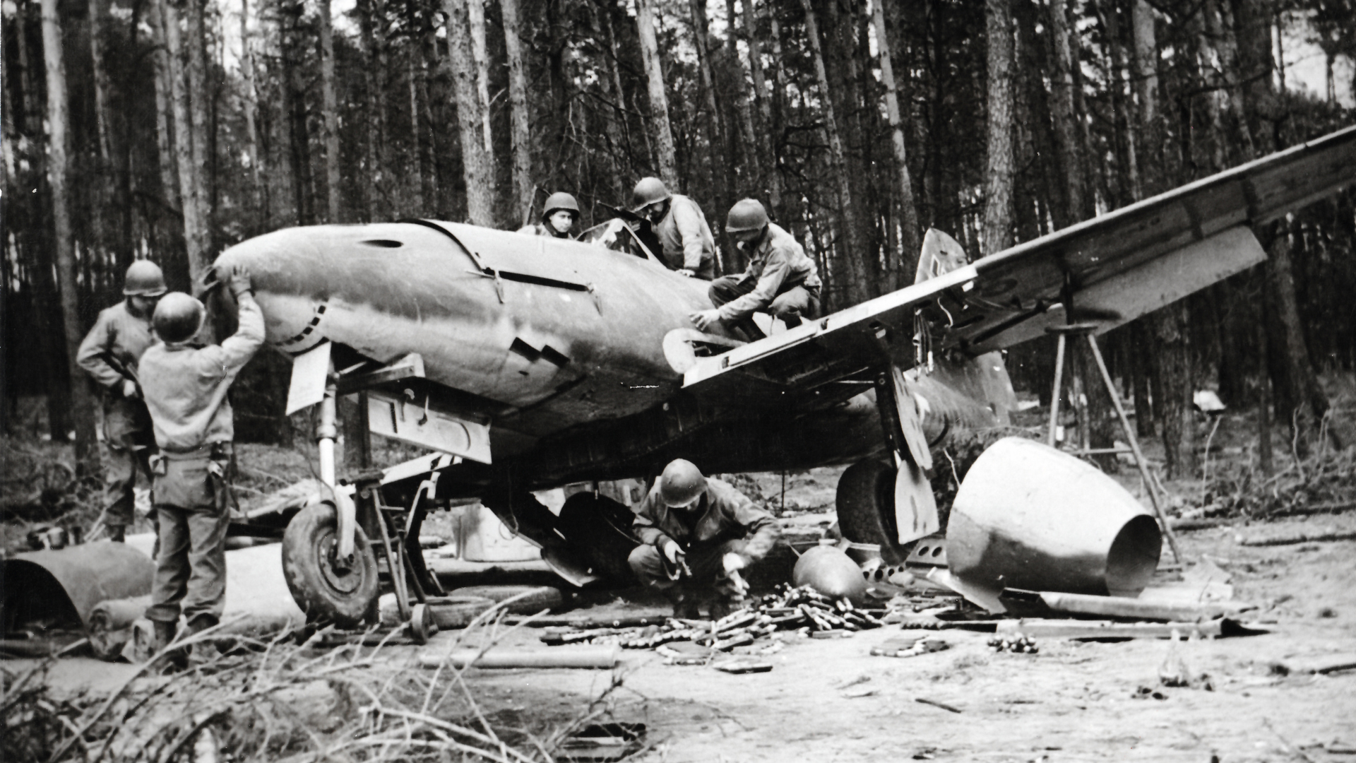 The trouble with souvenir hunting: GIs examine a Messerschmitt Me 262 jet fighter-bomber found in the closing days of the war in Germany.  This example was captured sans engines, but with plenty of 30mm ammunition for the jet’s MK 108 cannons.