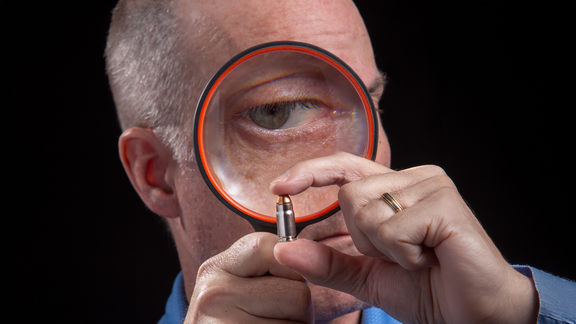 man inspecting a cartridge with a magnifying glass
