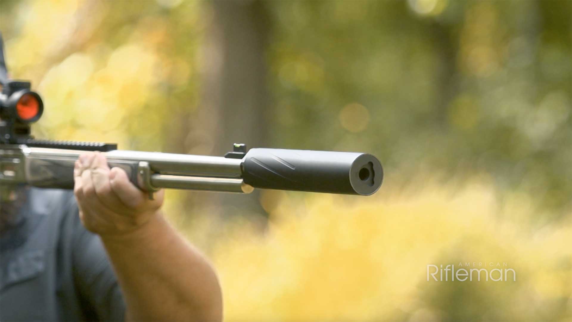 A man aims a rifle equipped with a Silencer Central Banish 46 suppressor.