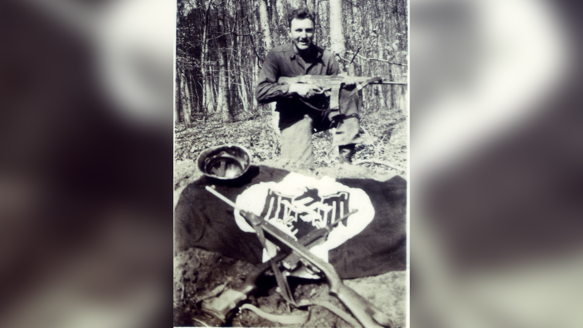 A GI poses with a captured Nazi flag, helmet, and StG44 automatic rifle.