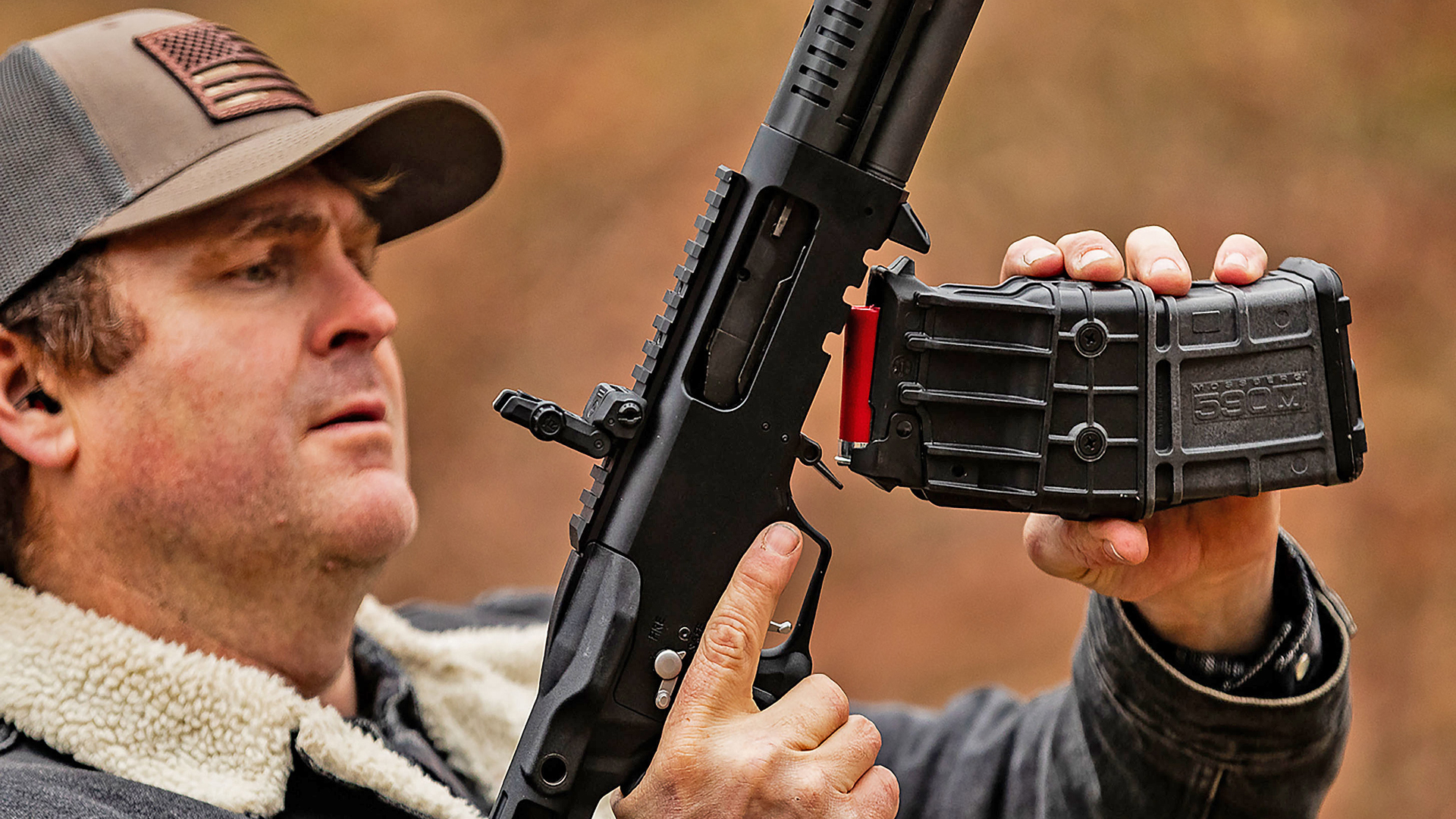 New For 2025: Mossberg 590 rotary safety pump-action shotgun shown with detachable box magazine inserted by man outdoors