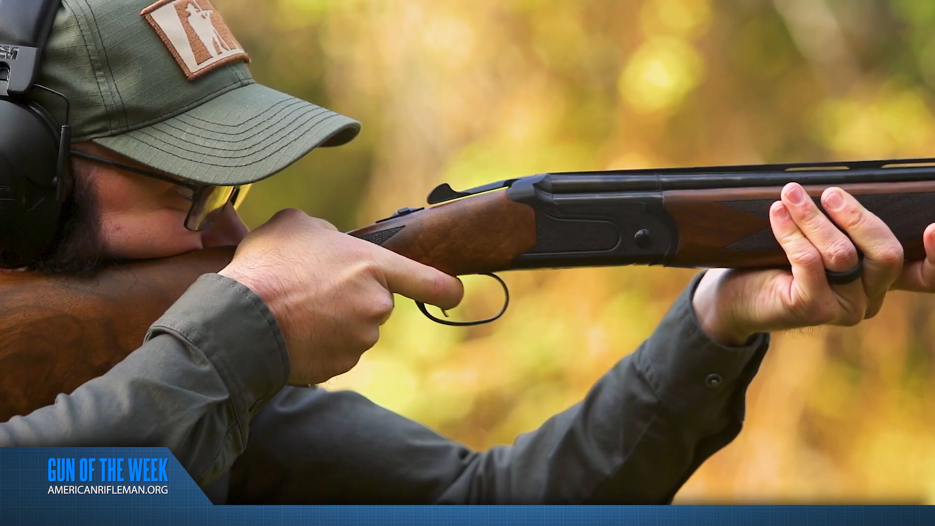 GUN OF THE WEEK text overlay man shooting Mossberg Gold Resereve Black 20-ga. shotgun with walnut stock outdoors