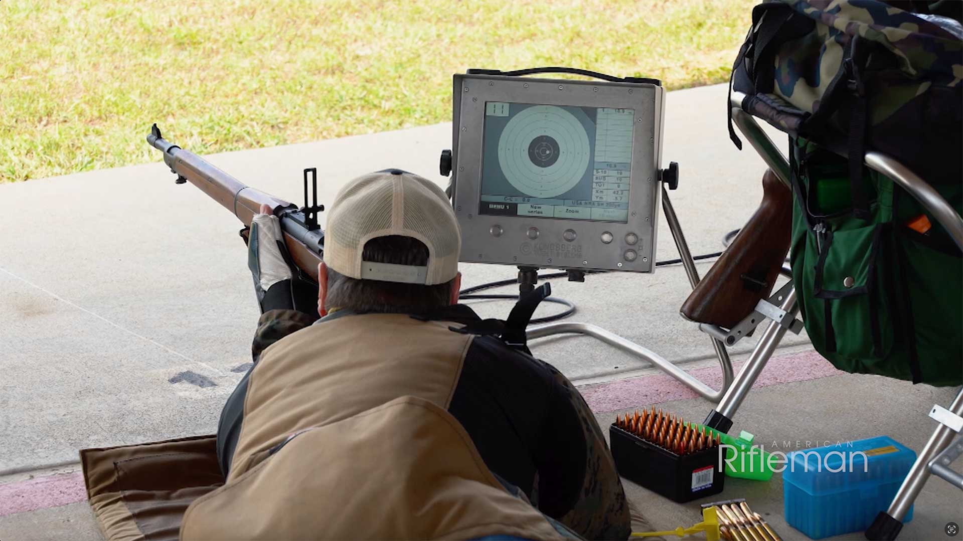 Man shooting an M1903 Springfield rifle with an electronic target display to his right.