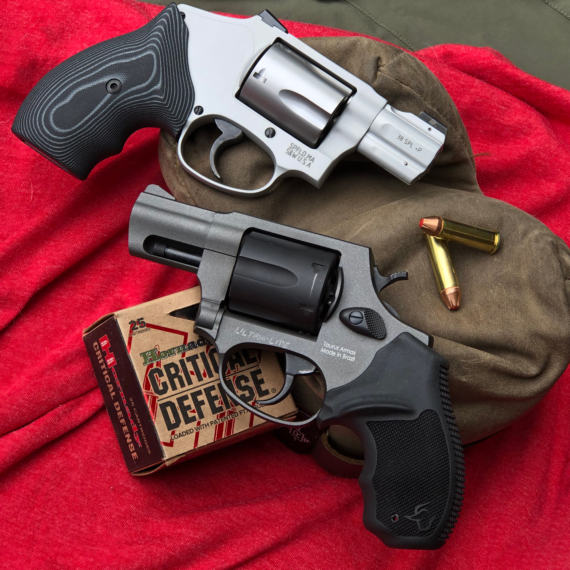 Snub-nose revolvers stainless steel black finish two guns shown with hornady critical defense ammunition adn red background