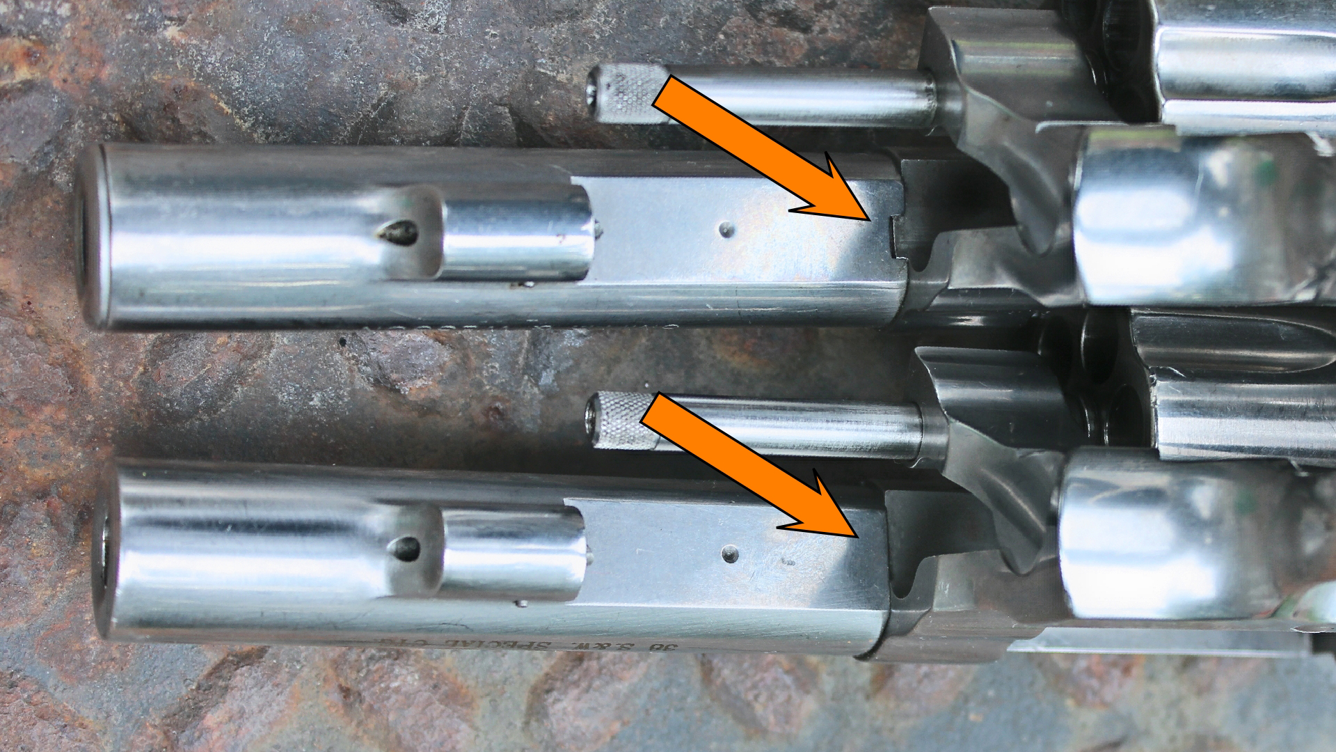 Smith & Wesson Model 64 648 side-by-side comparison stainless steel revolver barrel underside view shown with arrows illustrating mating surfaces of barrel shroud shown on rusted treadplate background