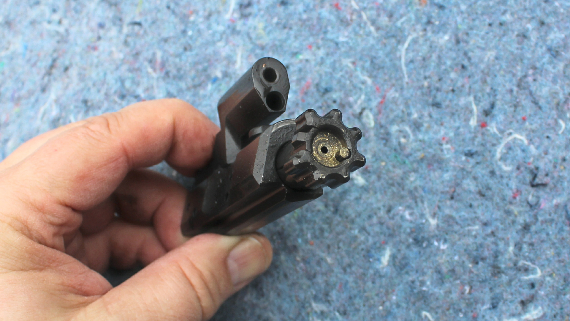 Review: Global Ordnance Monolith Bufferless bolt face angled in hand illustrating components of BCG with blue background