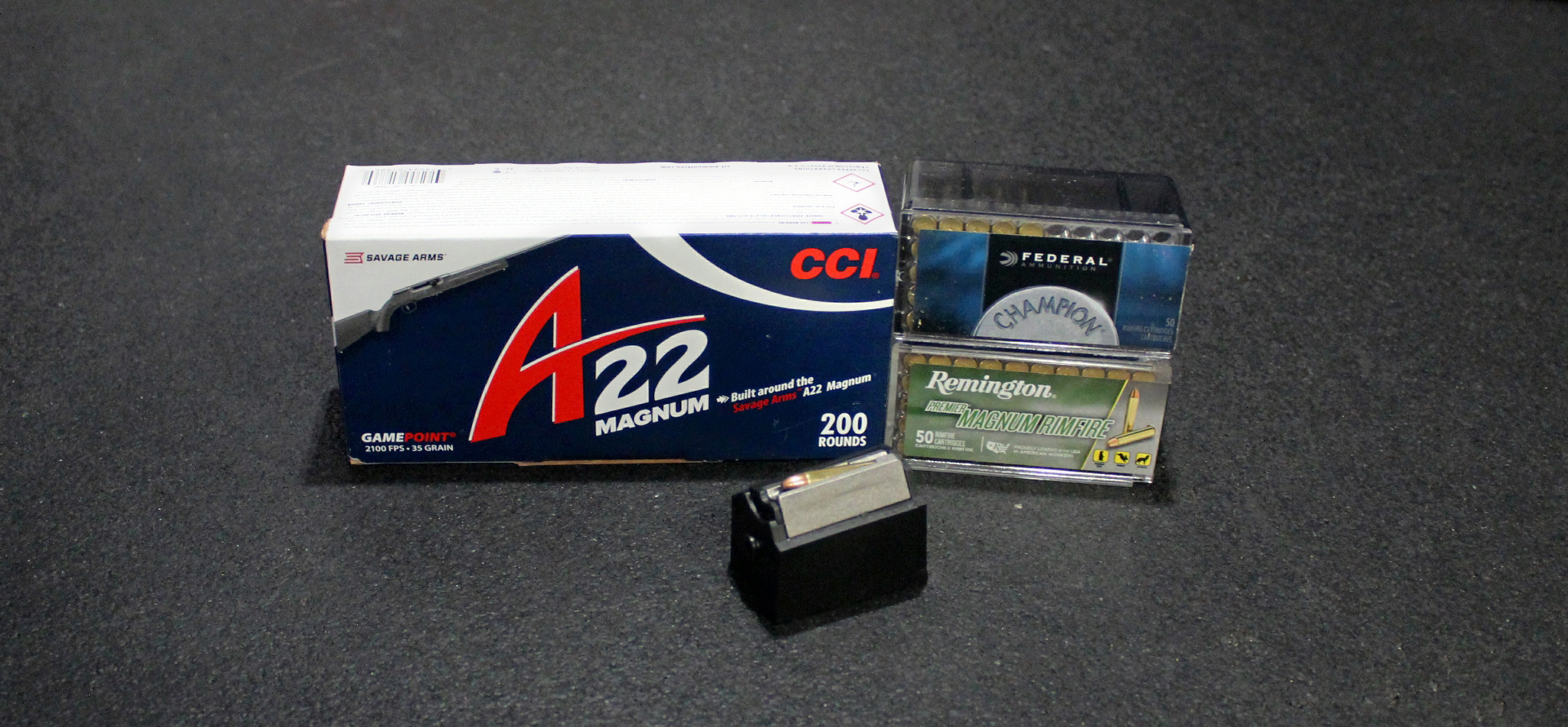 Boxes of .22 WMR ammunition on dark table shown with rotary magazine front and center