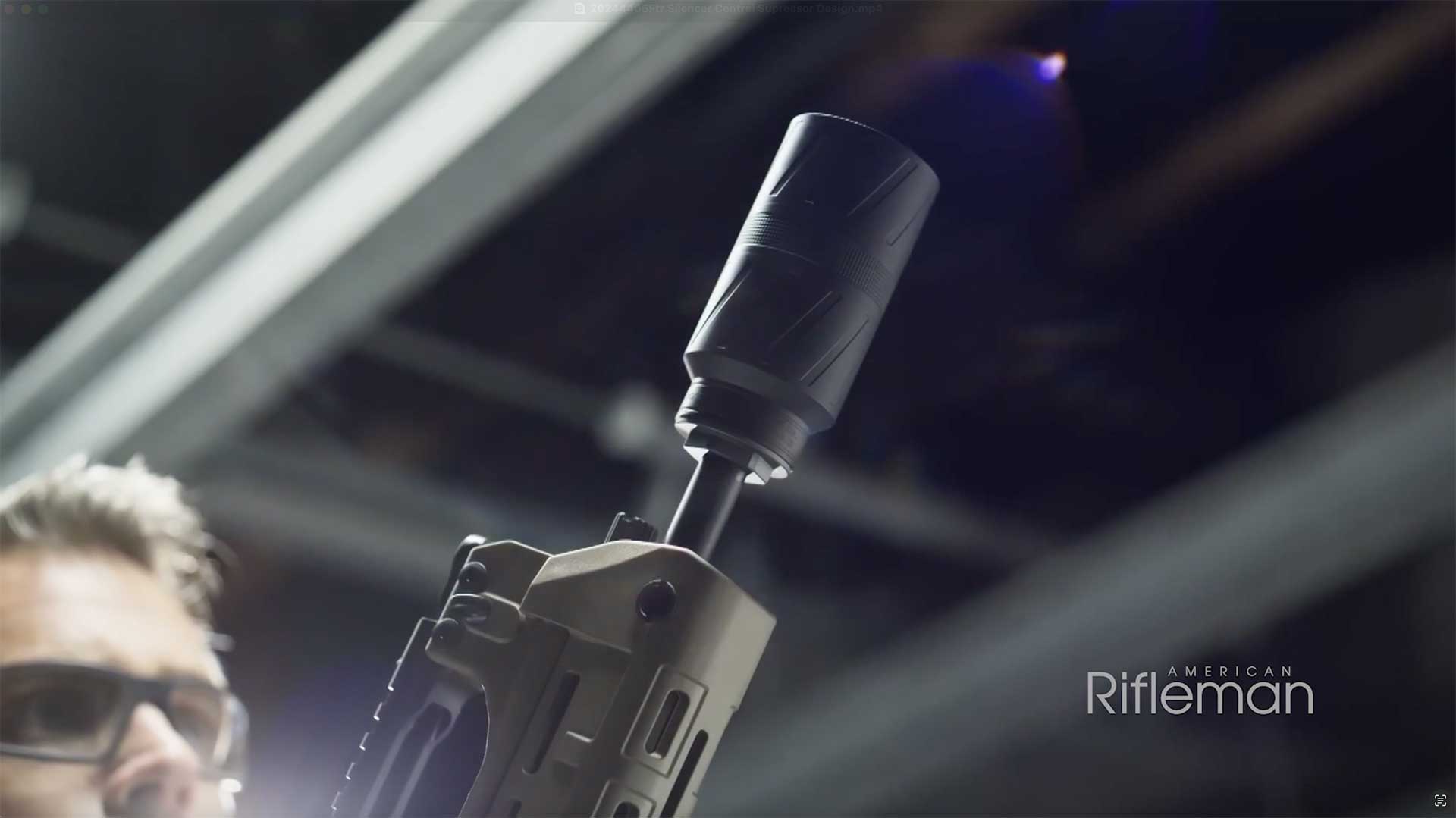 Man looking at a Silencer Central Speed K suppressor on the end of a rifle.