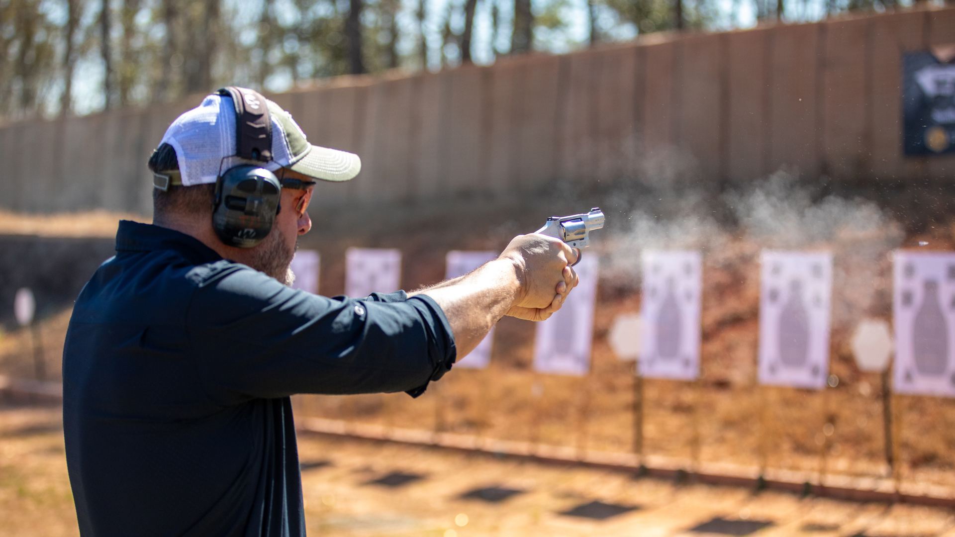 Author firing Smith & Wesson Ultimate Carry Revolver j-frame targets smoke gun man wearing cap and ear protection eye protection outdoors