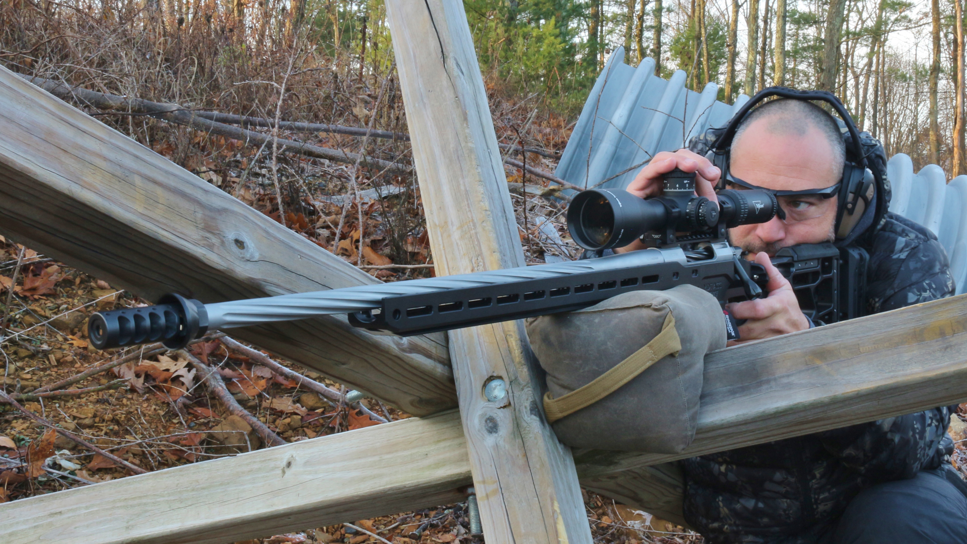 Man behind bolt-action rifle at tank trap adjusting riflescope