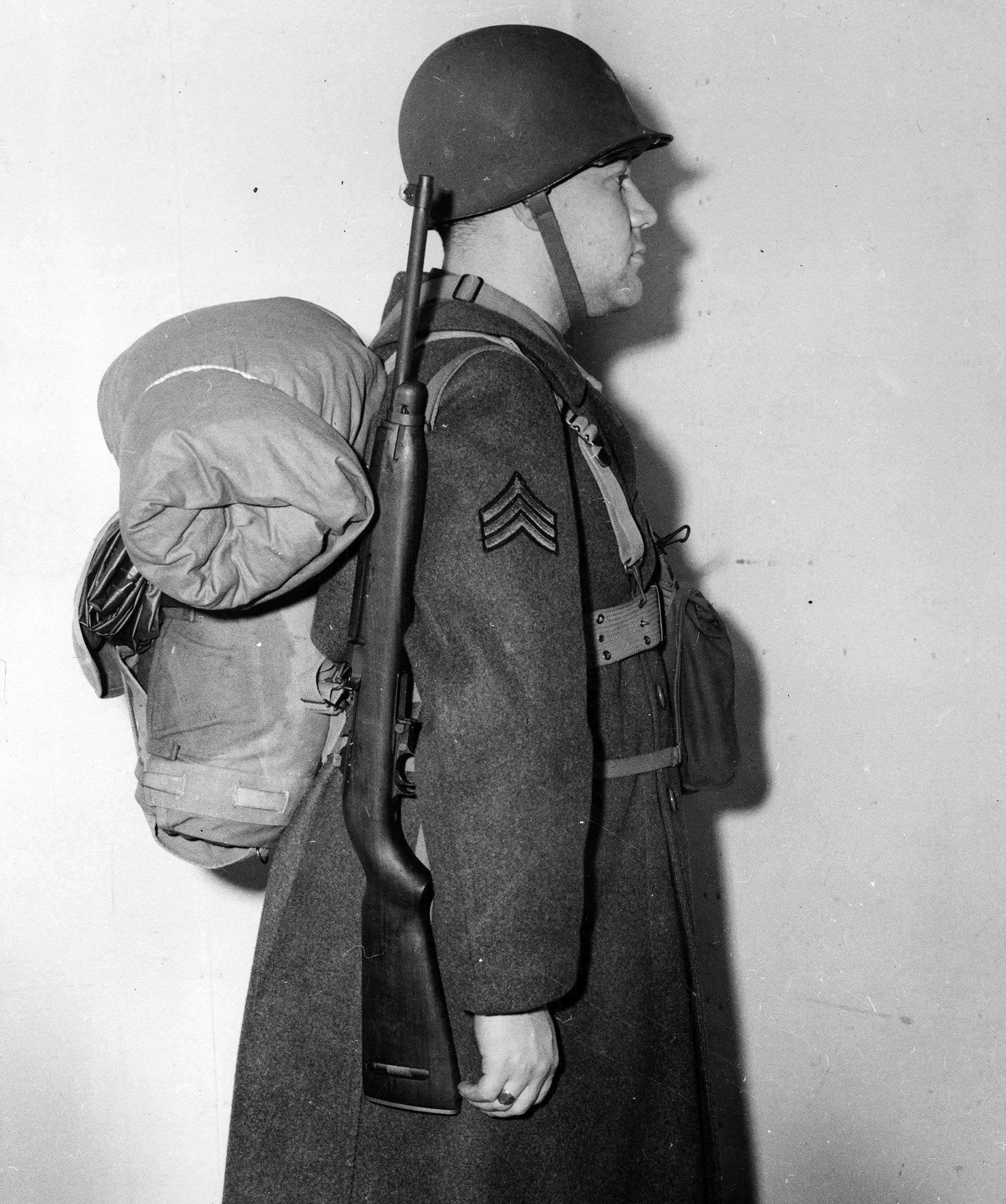 A World War II soldier shown with a slung M1 carbine and equipment pack.