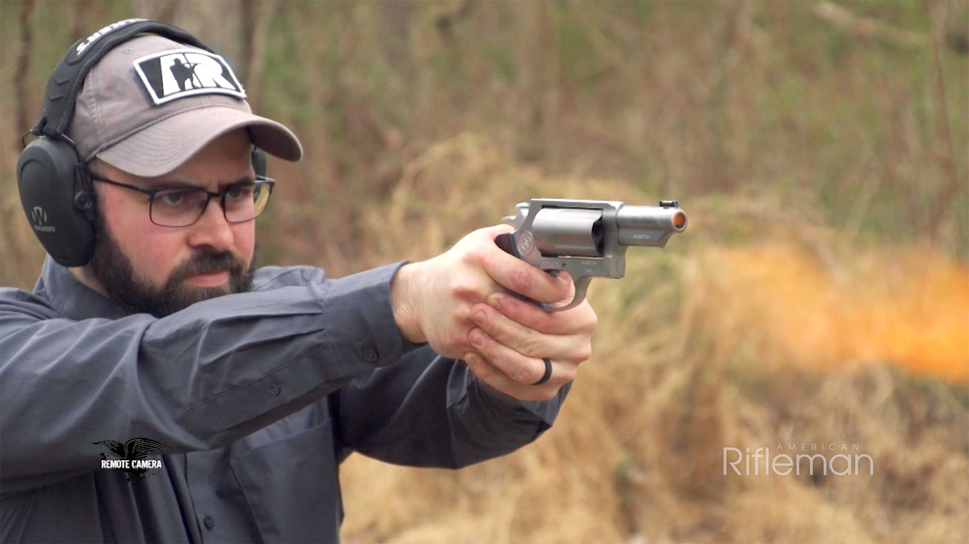 A man firing the Taurus Judge Executive Grade revolver on an outdoor range.