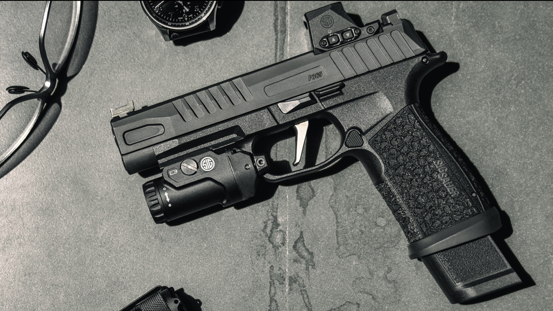 SIG Sauer P365-FUSE laying on a stone surface next to a watch and sunglasses.