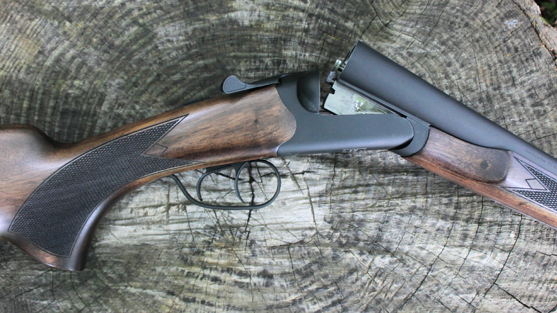 Heritage Badlander shotgun action open closeup shown resting on log outdoors