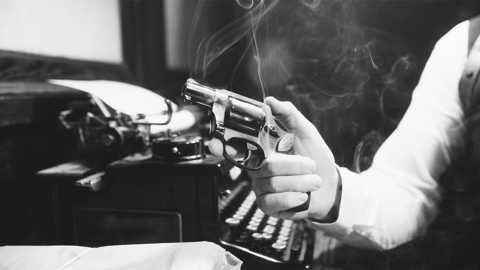 A black-and-white photo of a man holding a Heritage Mfg. Roscoe over a typewriter.