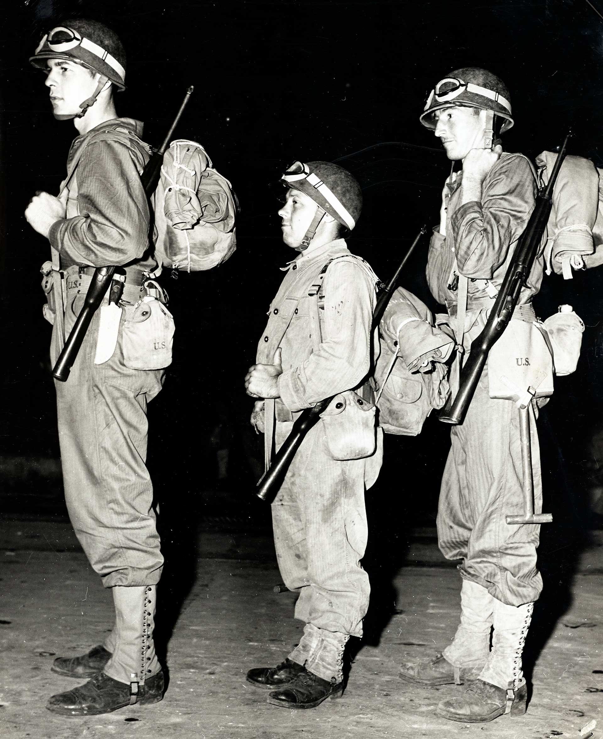 Three men of different heights armed with the M1 carbine and other military accoutrements.