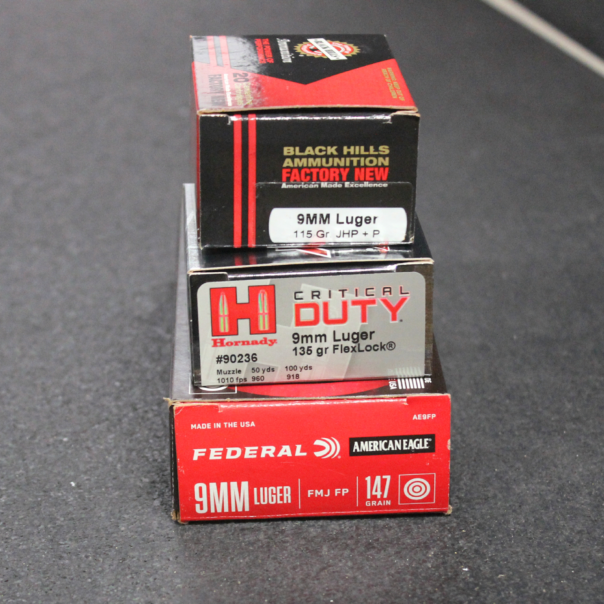 three 9 mm ammunition boxes black hills hornady federal stacked on black table