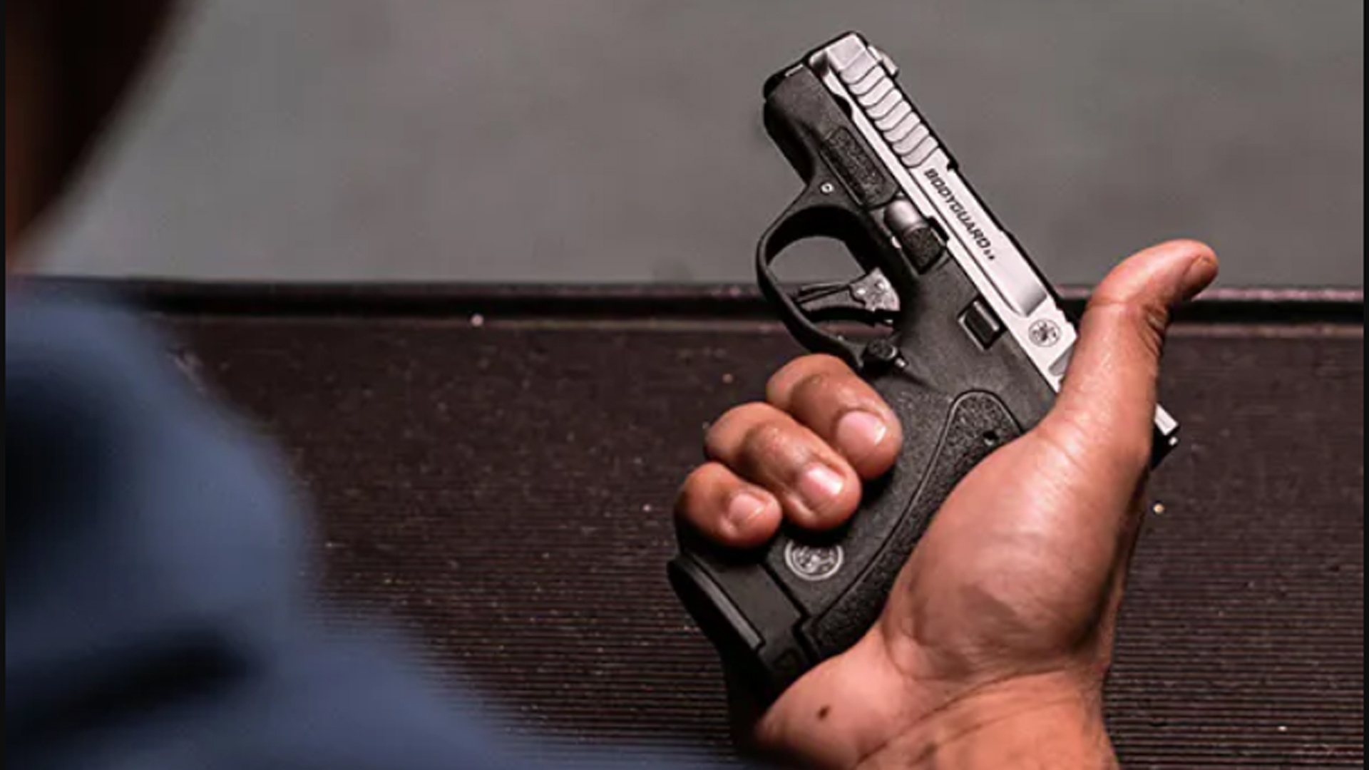 A man holding a Smith & Wesson Bodyguard 2.0 in his right hand.