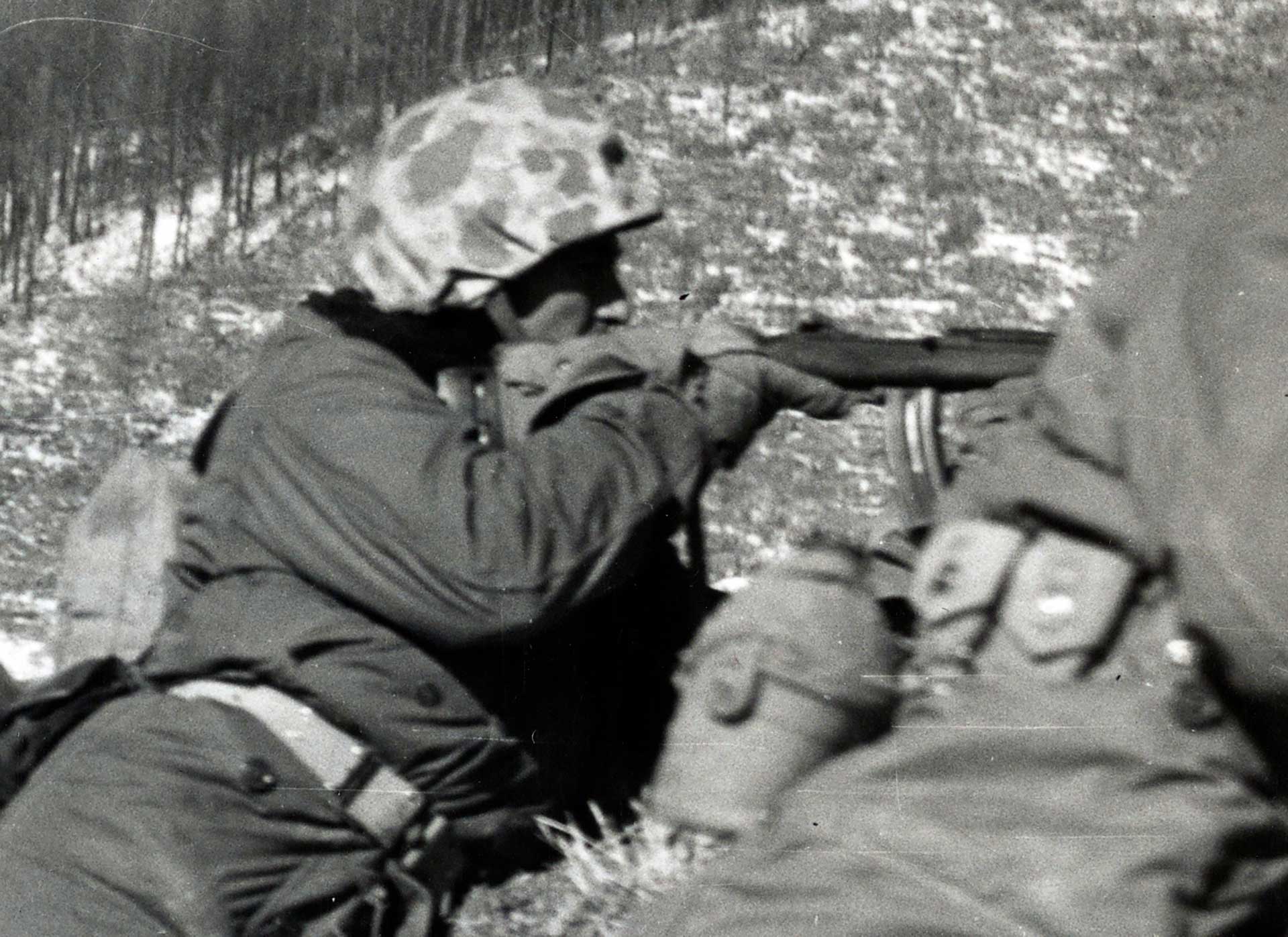 A U.S. Marine aims his M2 carbine in the snowy woodlands of Korea.