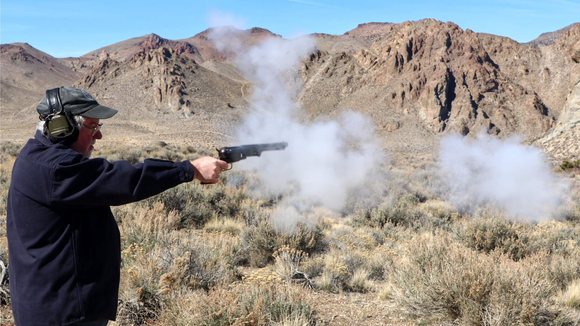 Man outdoors in mountains shooting blackpowder revolver