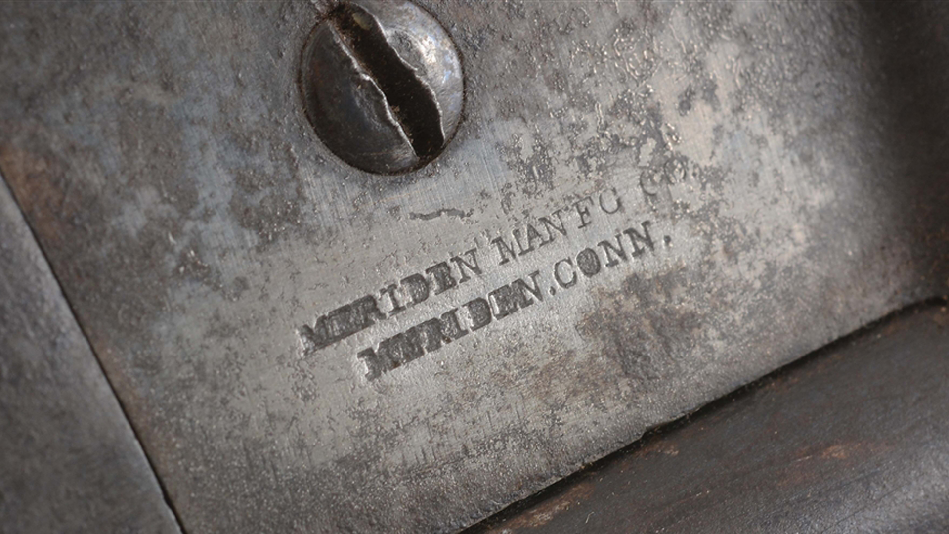 Metal gun receiver and screw with stamping text "MERIDEN MANFG, MERIDEN, CONN."