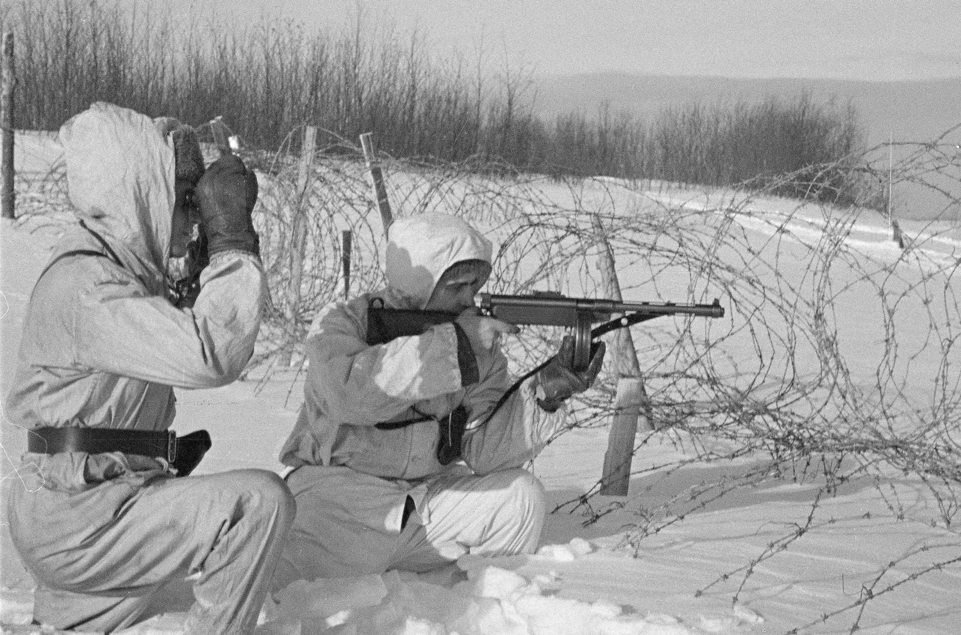 Finnish Suomi 9 mm KP/31 soldiers in snow barbed wire rolling hills trees background