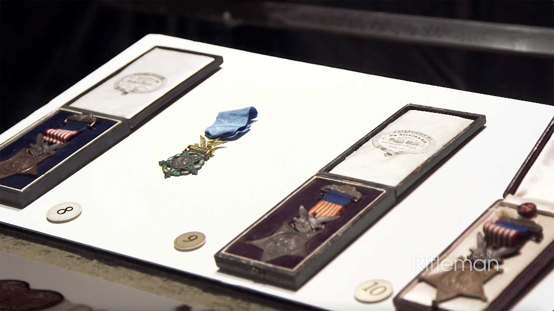 Medals laying inside a display case on a white backer board.