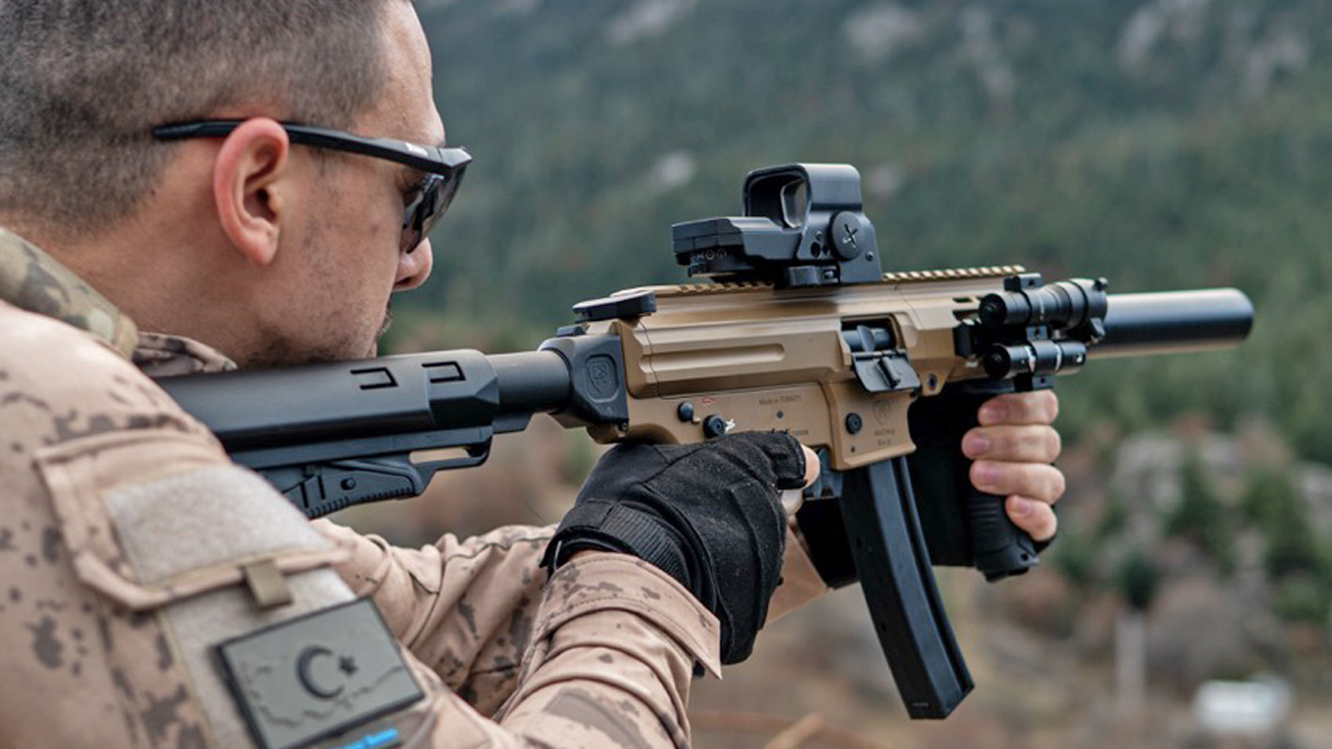 Turkish man wearing camouflage shooting a tan-colored model of the MAC IX.