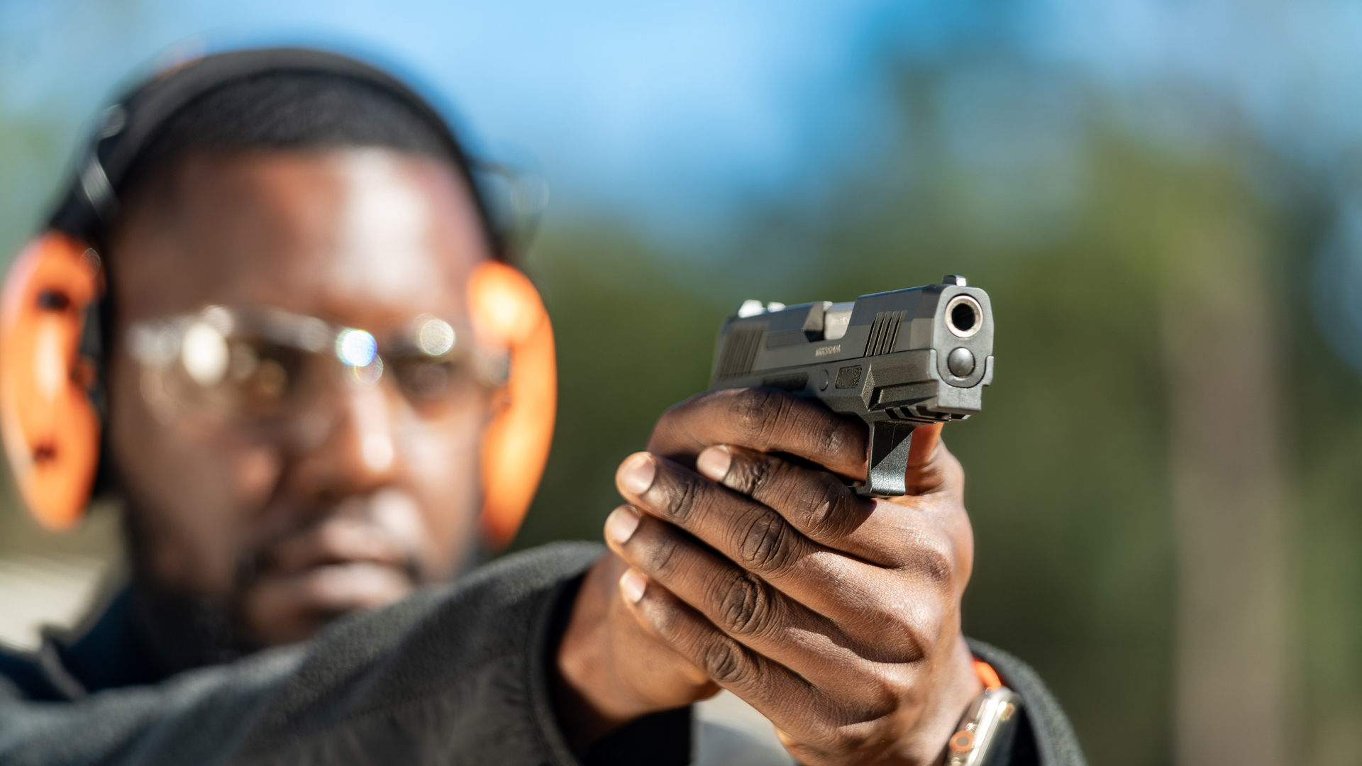 Man wearing orange earmuffs shooting a Taurus GX2 handgun.