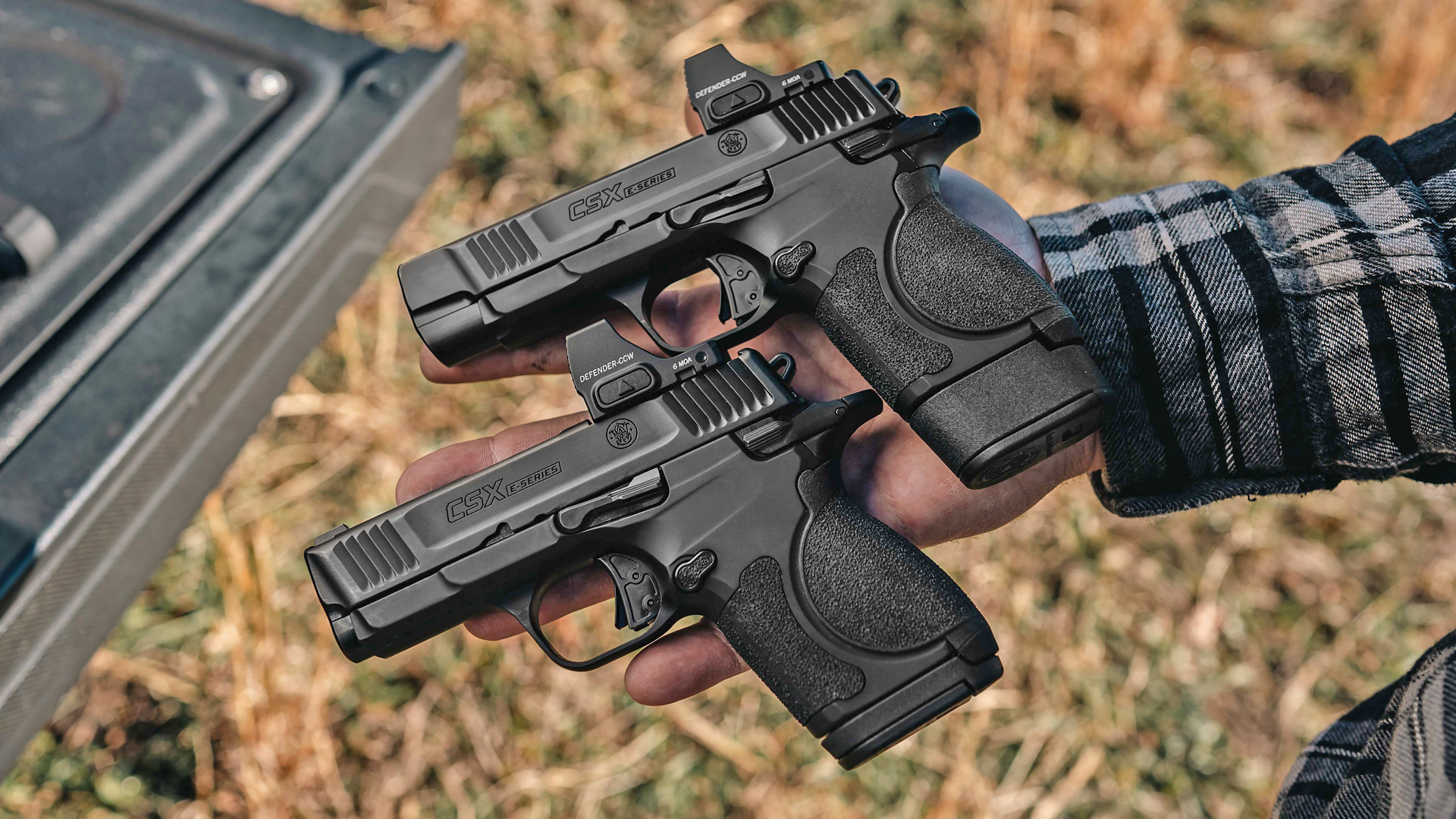 Man showing both models of the Smith & Wesson CSX E-Series in an open hand while standing behind a truck bed.