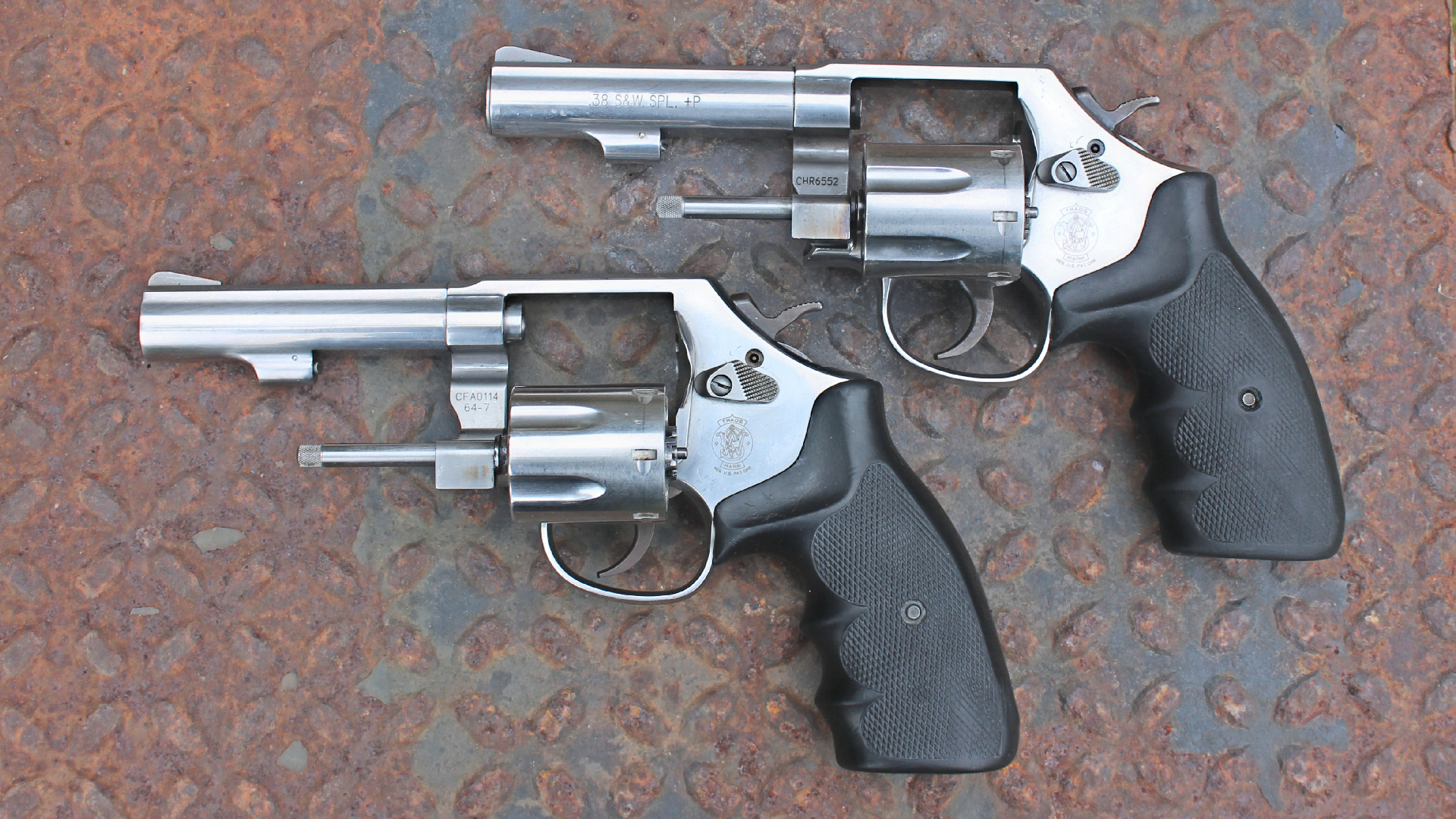 A closer look at the Model 64-7 (Bottom) and 64-8 stainless steel Smith & Wesson revolver (Top) reveals cosmetically subtle but mechanically significant differences in their configurations shown on rusted treadplate.