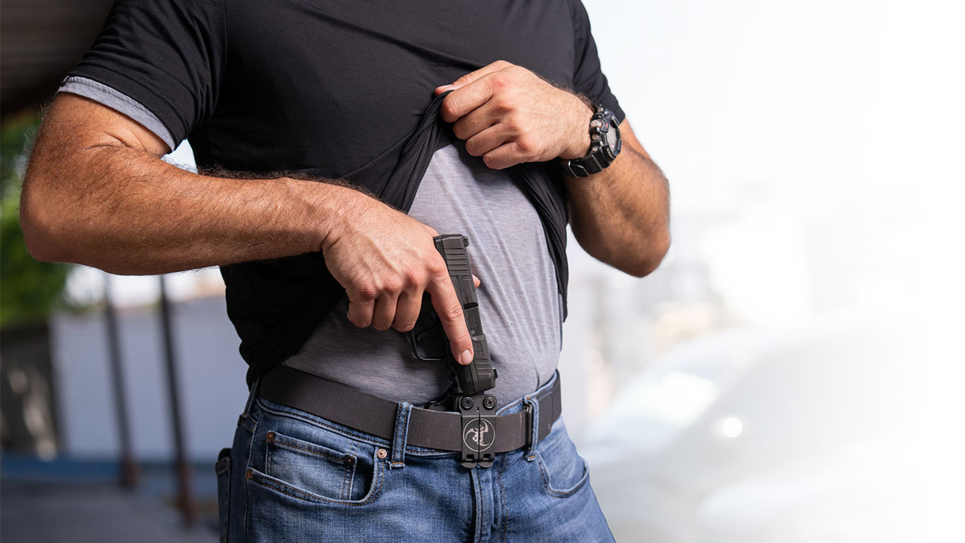 Man holstering the Heckler & Koch CC9 in an appendix-carry holster.